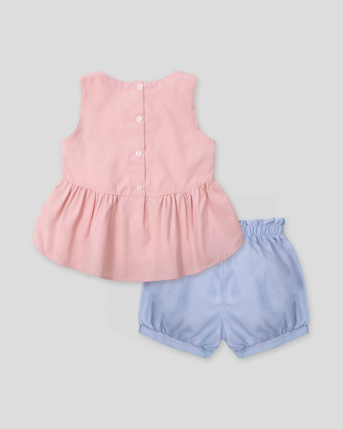 Conjunto blusa rosa pastel con moñito estampado, botonadura en espalda y short azul para bebé niña