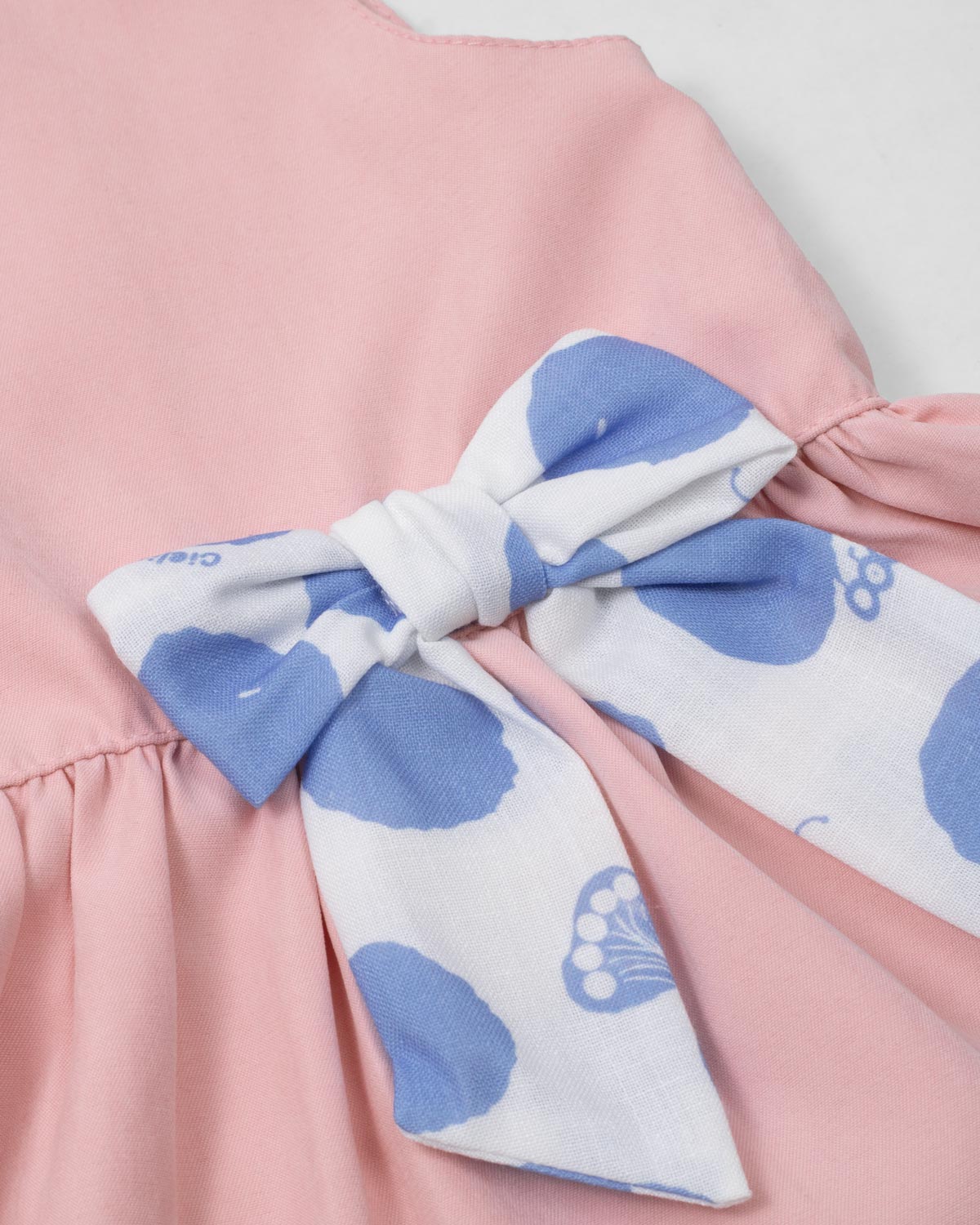 Conjunto blusa rosa pastel con moñito estampado, botonadura en espalda y short azul para bebé niña