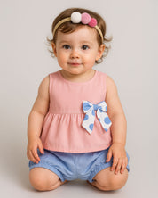 Conjunto blusa rosa pastel con moñito estampado, botonadura en espalda y short azul para bebé niña