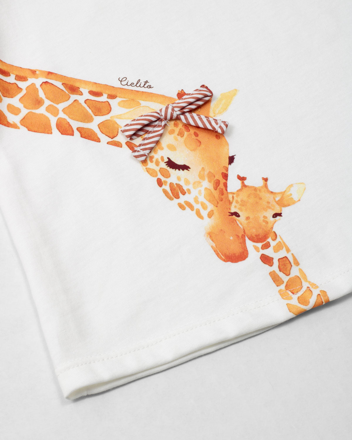 Conjunto blusa blanca con estampado de jirafas y short de líneas naranja para bebé niña