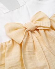 Vestido body en lino blanco y amarillo con detalle de moño para bebé niña