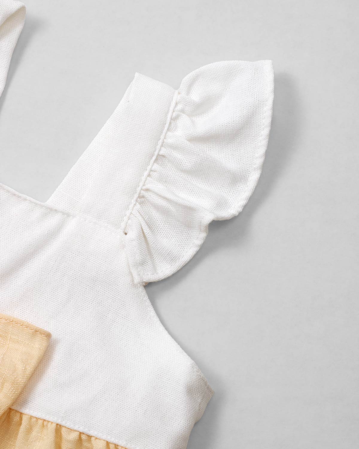 Vestido body en lino blanco y amarillo con detalle de moño para bebé niña