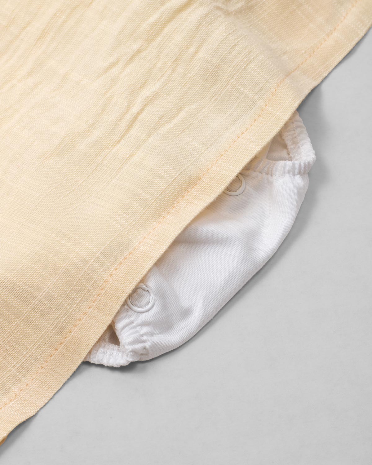 Vestido body en lino blanco y amarillo con detalle de moño para bebé niña