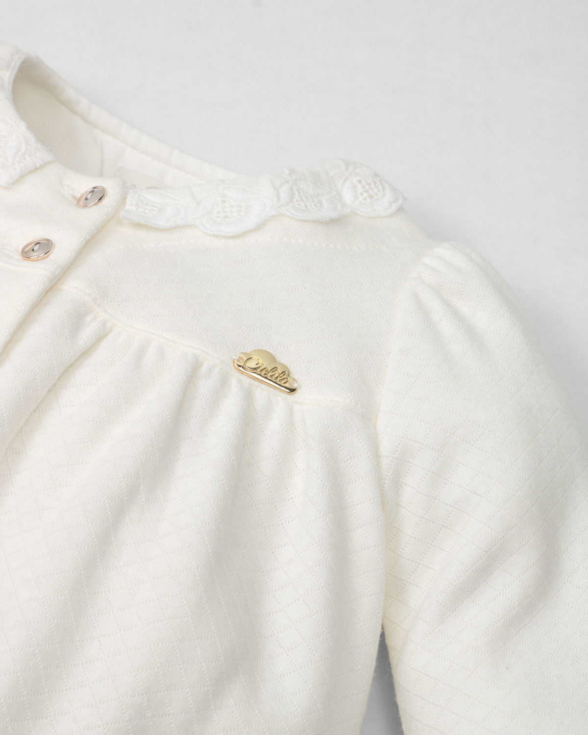 Pijamas enteriza blanca crema con botones y corazones en los costados para bebé niña