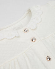 Pijamas enteriza blanca crema con botones y corazones en los costados para bebé niña