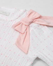 Pijama enteriza blanca con puntitos rosados, detalle de moño y botones para bebé niña