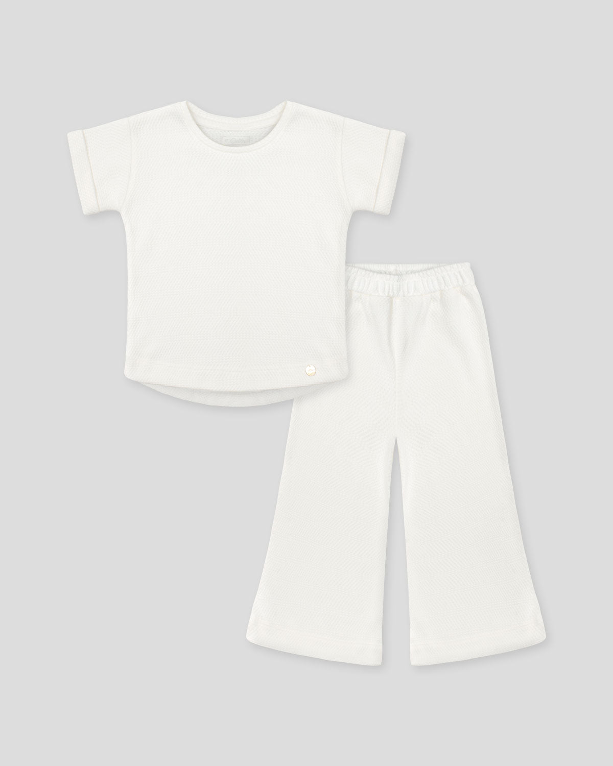 Conjunto blusa y pantalón blancos en tejido texturizado para niña