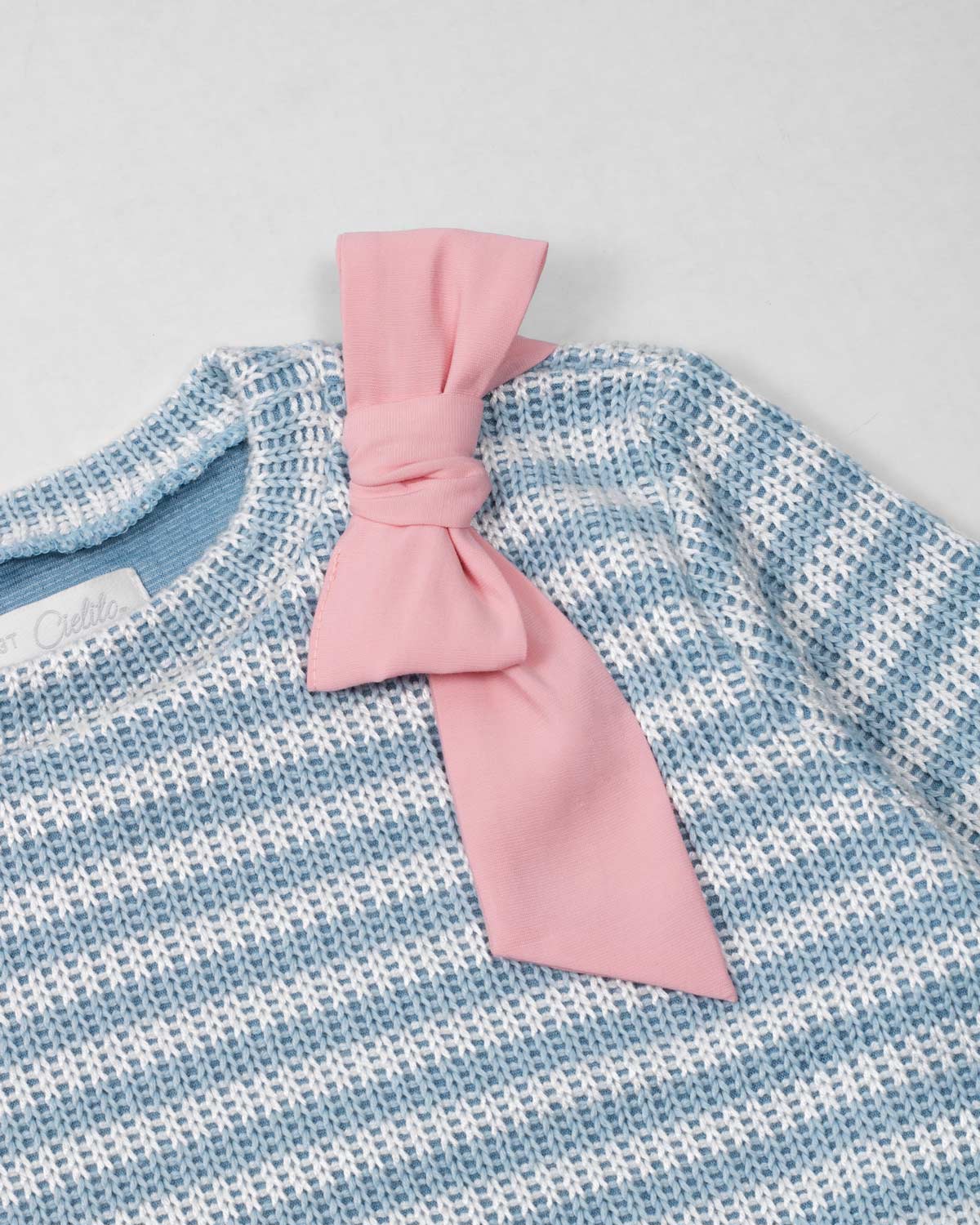 Saco en tela tejita blanco y azul con moño rosado para niña