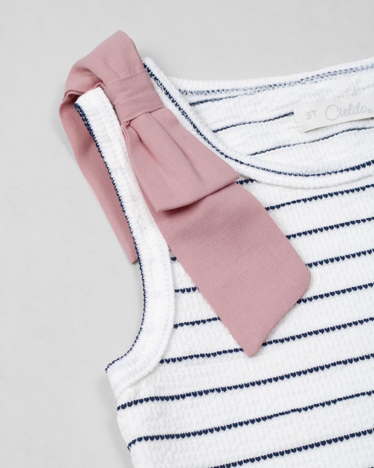 Blusa manga sisa blanca con líneas y moño rosa en hombro para niña