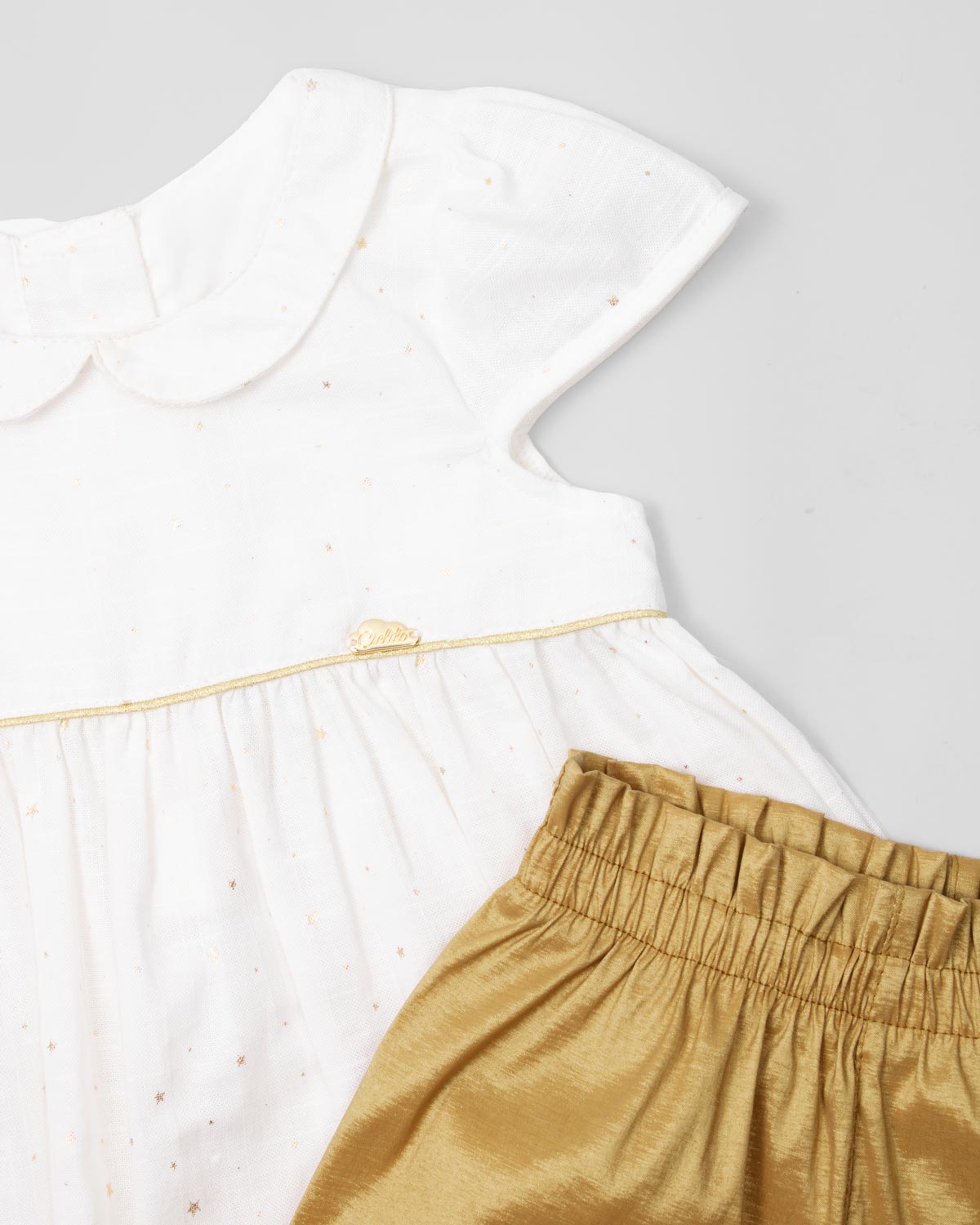 Conjunto blusa blanca en lino con estrellitas doradas, botonadura en espalda y short dorado para bebé niña