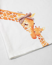 Conjunto blusa blanca con estampado de jirafas y short de líneas naranja para bebé niña