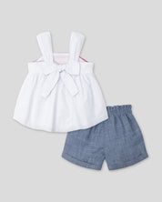 Conjunto blusa blanca de tiras con textura tejida, moño en espalda y short azul para bebé niña