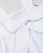 Conjunto blusa blanca de tiras con textura tejida, moño en espalda y short azul para bebé niña