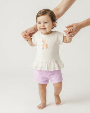 Conjunto blusa crema con estampado de conejitos y short lila para bebé niña