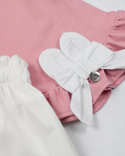 Conjunto blusa palo de rosa con moño y short blanco para bebé