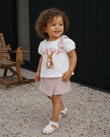 Conjunto blusa blanca estampada con moñito en hombro y falda short rosa para bebé niña