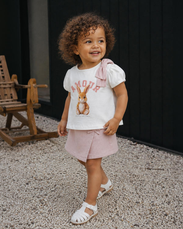 Conjunto blusa blanca estampada con moñito en hombro y falda short rosa para bebé niña
