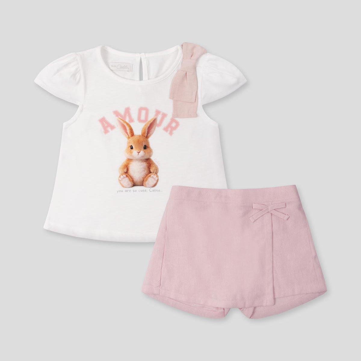 Conjunto blusa blanca estampada con moñito en hombro y falda short rosa para bebé niña