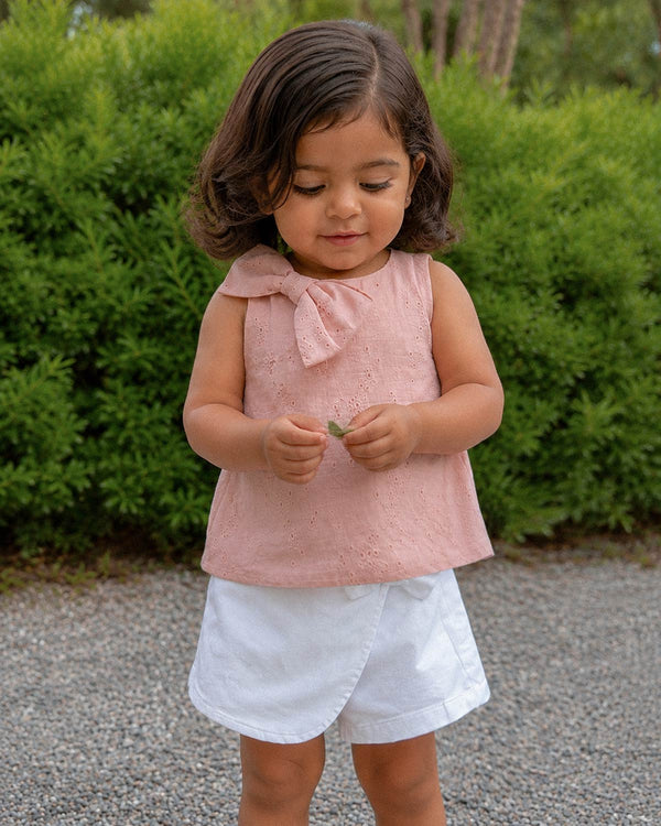 Conjunto blusa rosa con moño en tela hoja rota y falda short blanca para bebé niña