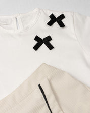 Conjunto camiseta blanca con moños negros y falda short crema para bebé niña