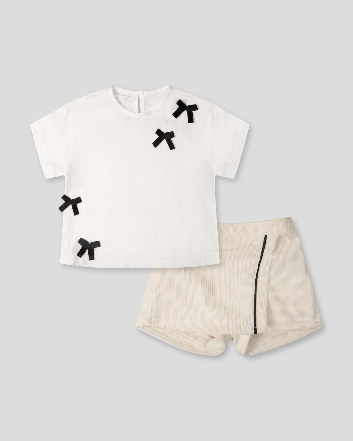 Conjunto camiseta blanca con moños negros y falda short crema para bebé niña