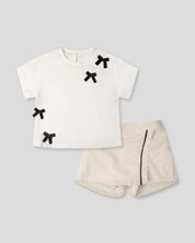 Conjunto camiseta blanca con moños negros y falda short crema para bebé niña