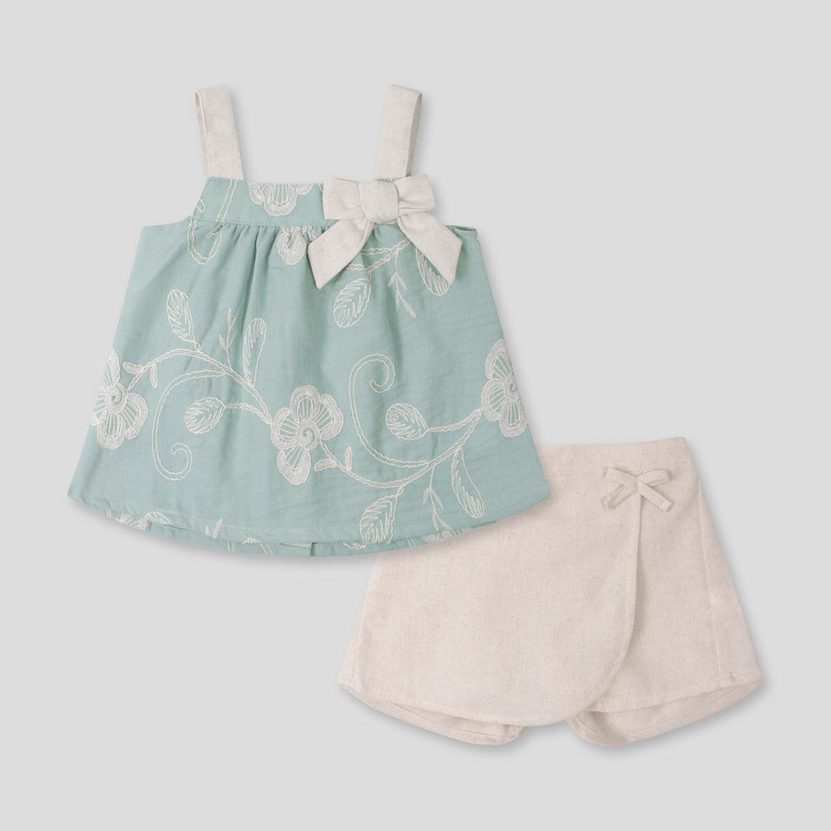 Conjunto blusa verde menta en tela bordada con moño y falda short crema para bebé niña