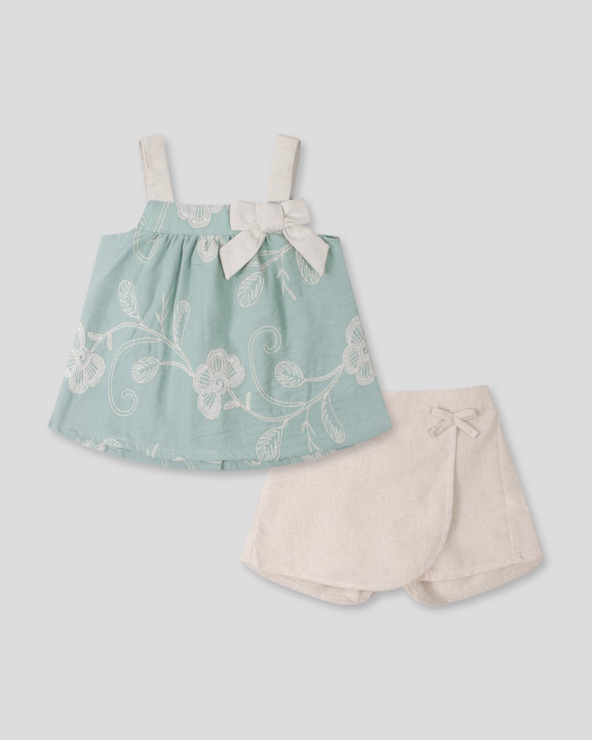 Conjunto blusa verde menta en tela bordada con moño y falda short crema para bebé niña