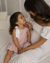 Vestido rosa en tela hoja rota con moño blanco en hombro para bebé niña
