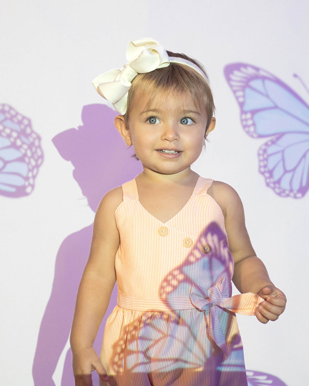 Enterizo corto de líneas naranjas con botones y detalle de moño en cintura para bebé niña