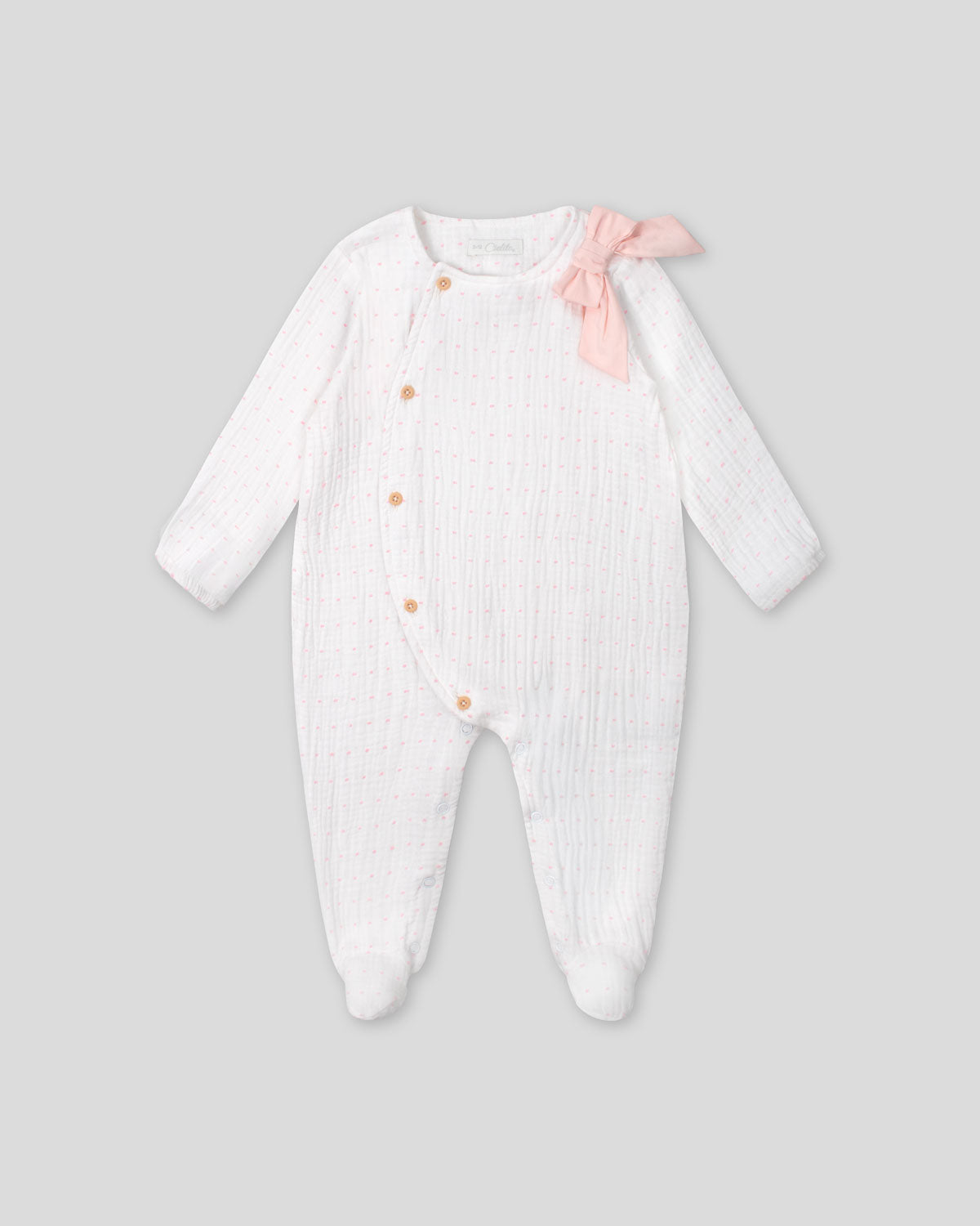 Pijama enteriza blanca con puntitos rosados, detalle de moño y botones para bebé niña