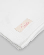 Ajuar blanco de dos piezas, gorrito y cobija para recién nacida.