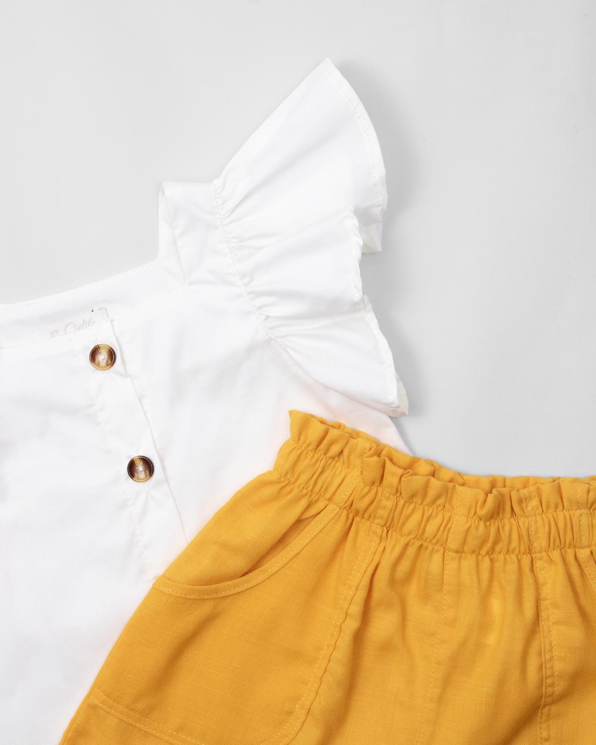 Conjunto blusa blanca con boleros en manga, botones y short amarillo para niña