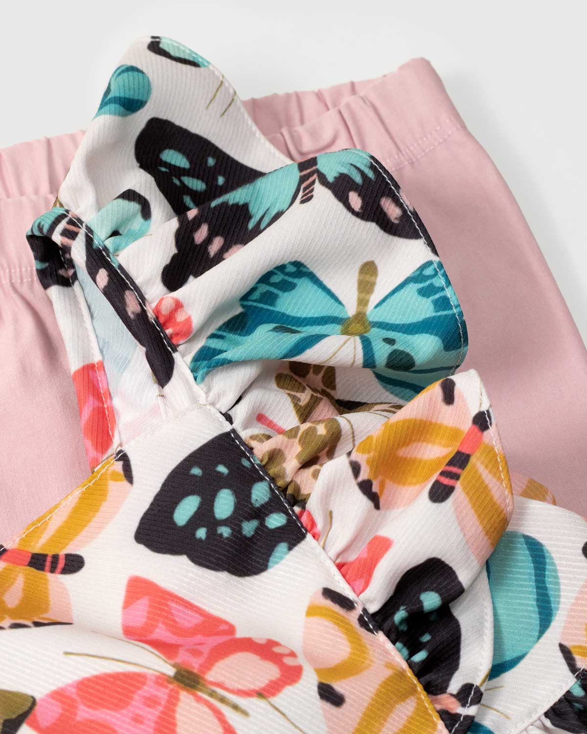 Conjunto blusa estampada de mariposas con bolero en manga, detalle de moño y leggins rosado para niña