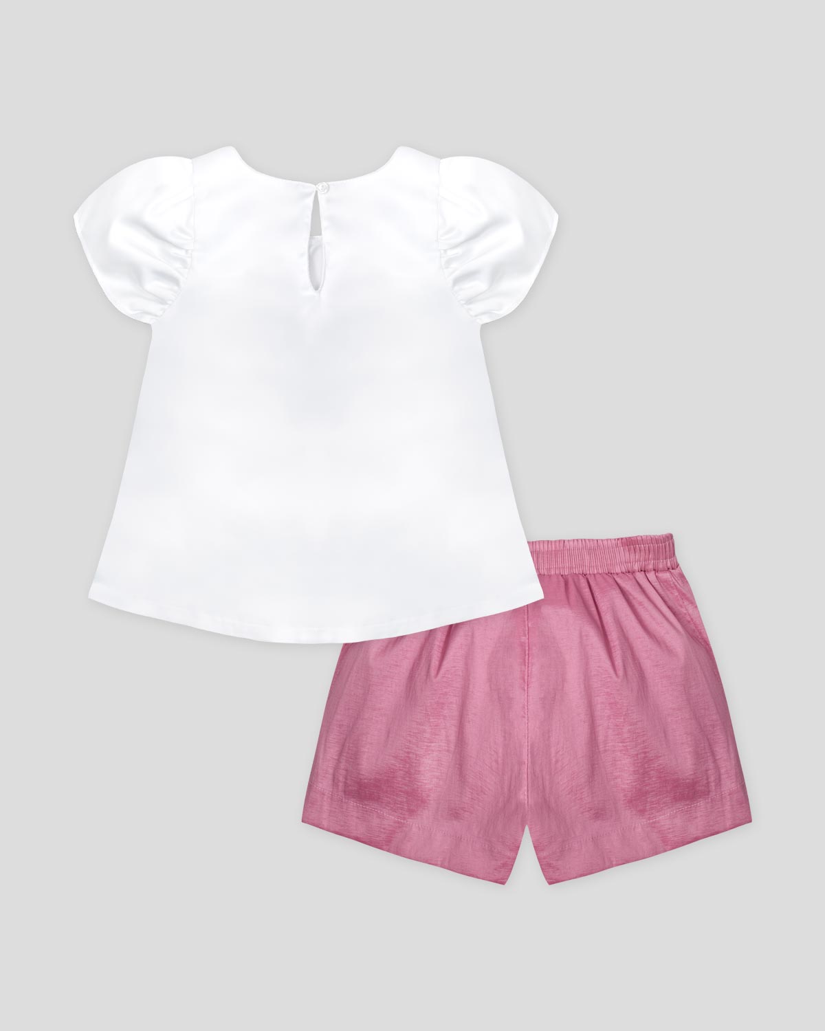 Conjunto blusa en satín blanco con aplique de moño y short rosado para niña