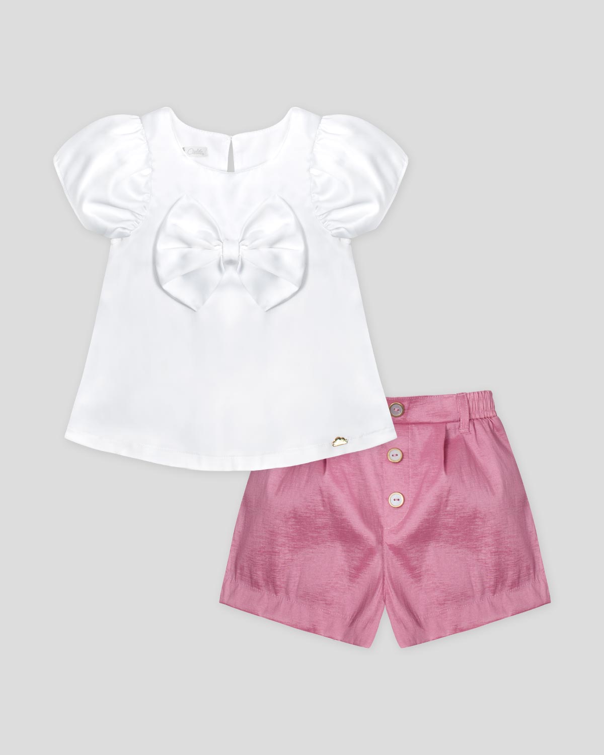 Conjunto blusa en satín blanco con aplique de moño y short rosado para niña