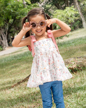 Conjunto blusa en lino con estampado de flores, tiras rosadas con moño y leggins azul para niña