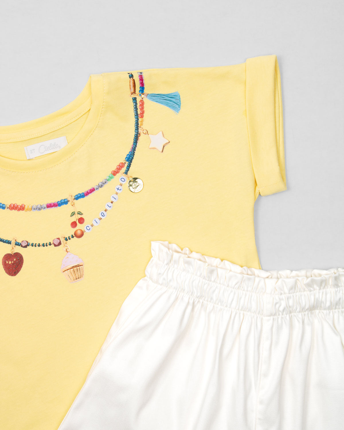 Conjunto camiseta amarilla con estampado, apliques y short blanco para niña