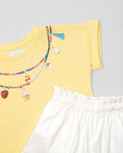 Conjunto camiseta amarilla con estampado, apliques y short blanco para niña