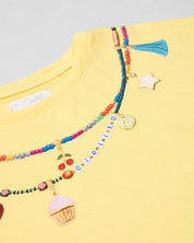 Conjunto camiseta amarilla con estampado, apliques y short blanco para niña
