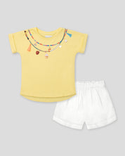 Conjunto camiseta amarilla con estampado, apliques y short blanco para niña