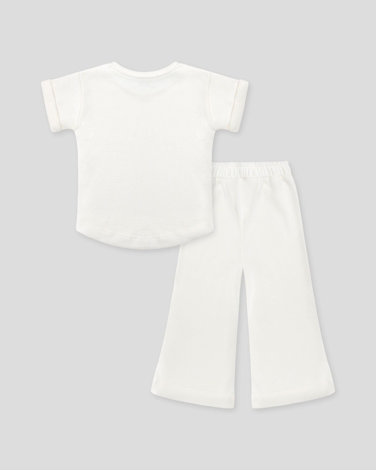 Conjunto blusa y pantalón blancos en tejido texturizado para niña