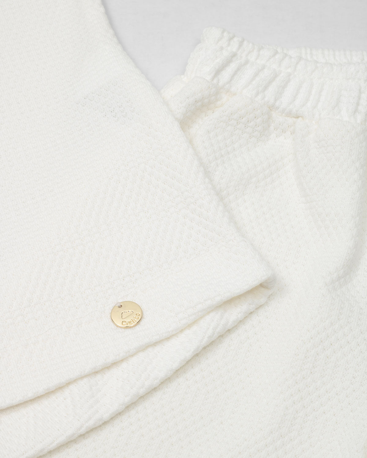 Conjunto blusa y pantalón blancos en tejido texturizado para niña