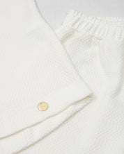 Conjunto blusa y pantalón blancos en tejido texturizado para niña