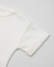 Conjunto blusa y pantalón blancos en tejido texturizado para niña