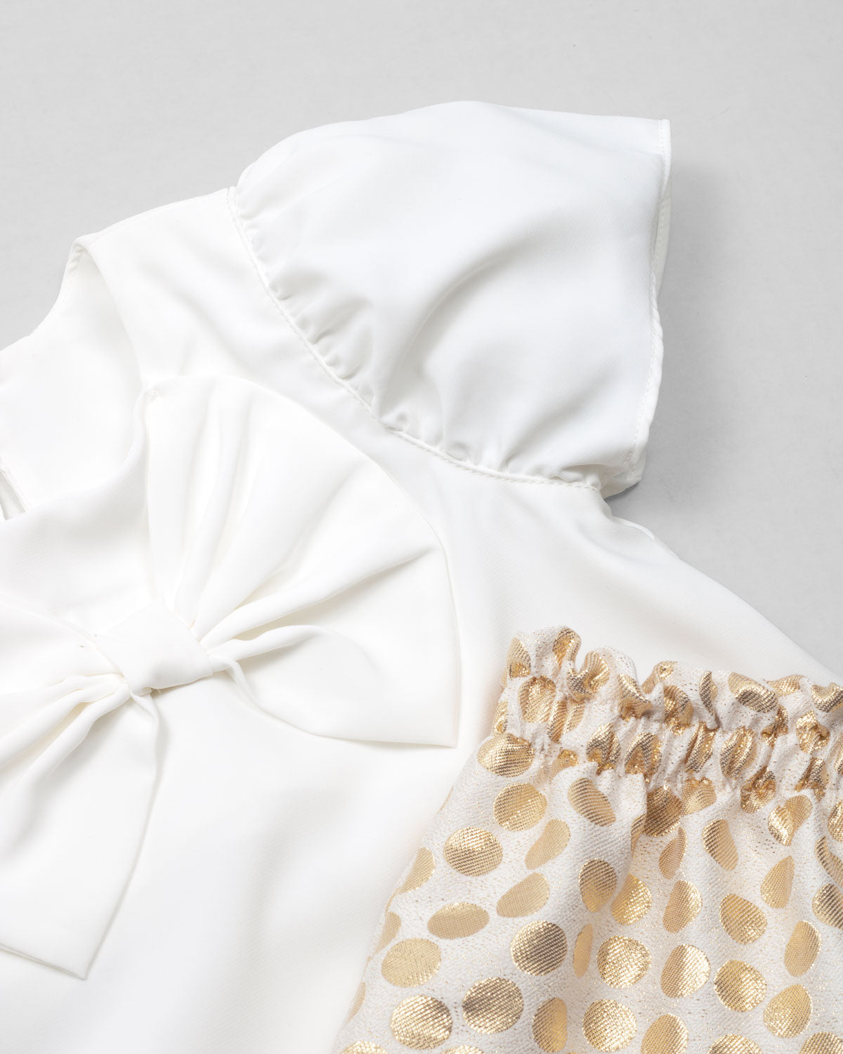 Conjunto blusa blanca en satín con moño y short de puntos dorados para niña