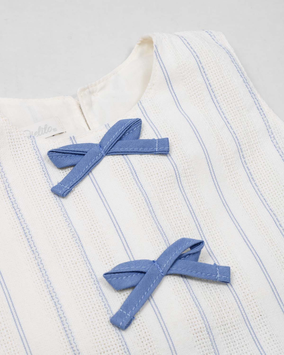 Conjunto blusa blanca con moñitos azules y falda short con prenses azul para niña