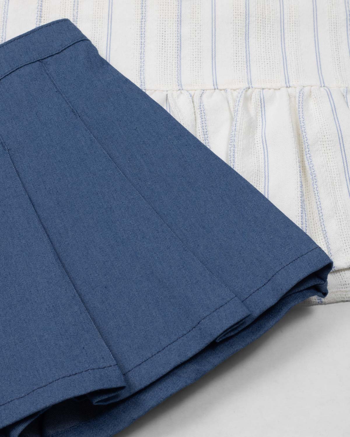 Conjunto blusa blanca con moñitos azules y falda short con prenses azul para niña