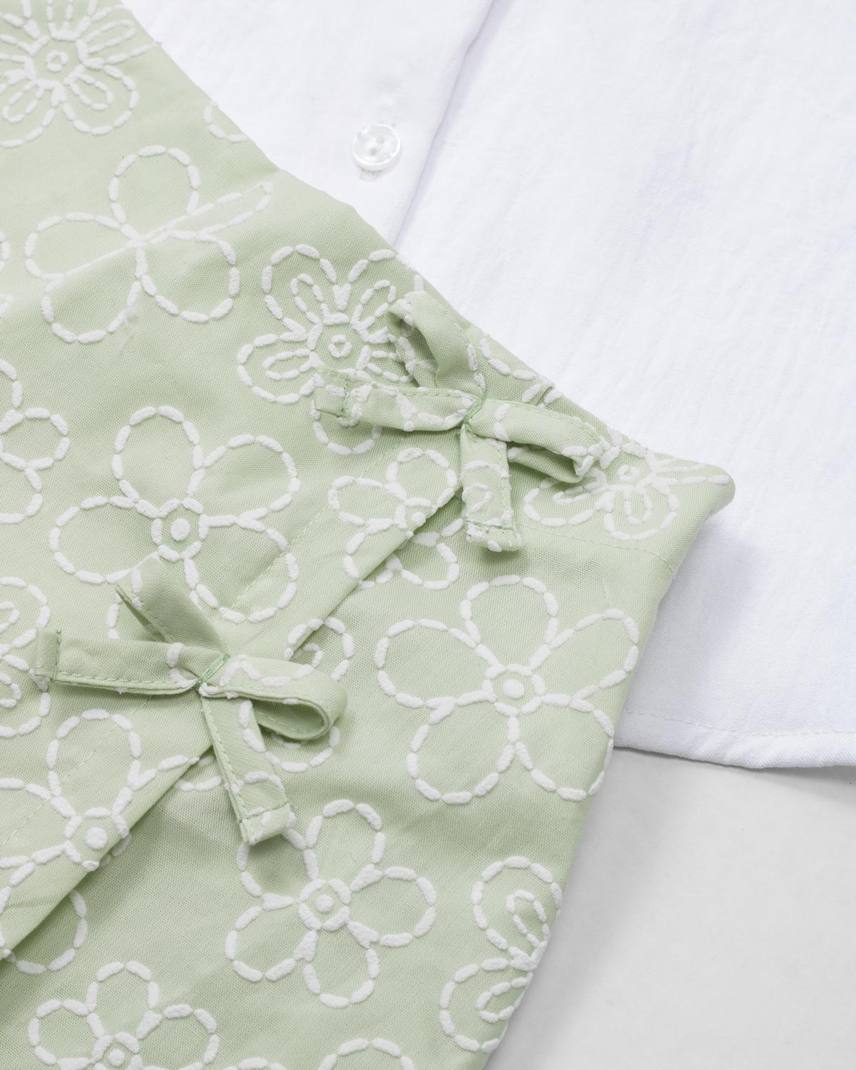 Conjunto blusa blanca con botones, moño y falda short verde estampado para niña