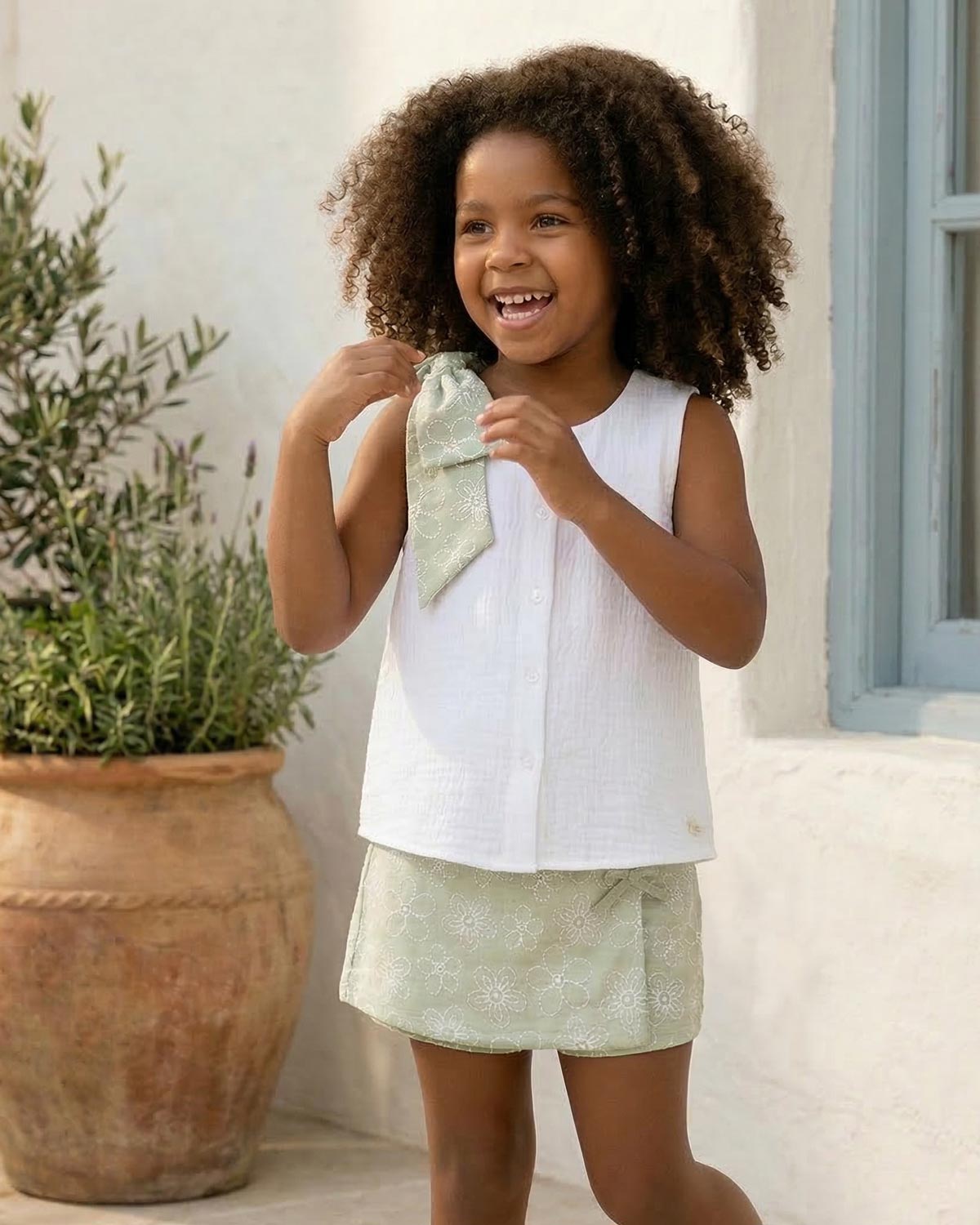 Conjunto blusa blanca con botones, moño y falda short verde estampado para niña
